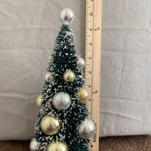 Bottle brush Christmas tree with gold and silver ornaments.